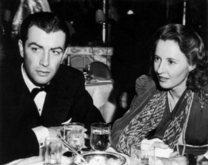  Married American actors Robert Taylor (1911-1969) and Barbara Stanwyck (1907-1990) sit at a table in a restaurant, wearing formal attire.  Stanwyck wears a cast on her forearm and uses a printed scarf as a sling.