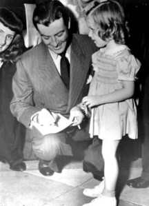 Robert Taylor signs an autograph for a little girl after leaving the HUAC hearings.